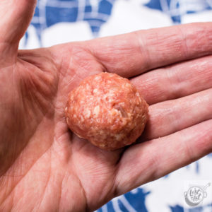 Meatball rolled into shape setting in a hand. Meatball rolled into shape setting in a hand.