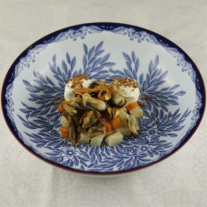 Placing the mussels on the carrots and celeriac in the bowl.